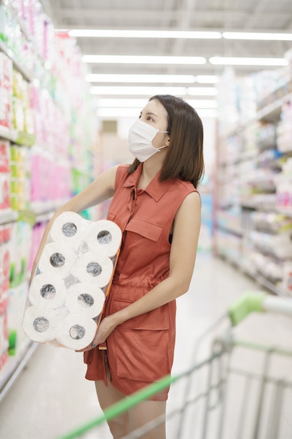 Covid-19-Ausbruch. Frau in der medizinischen Schutzmaskenpanik, die Seidenpapier kauft. Angst vor Coronavirus.