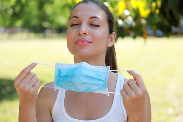 COVID-19 Deportiva mujer se quita la mascarilla quirúrgica de la cara y