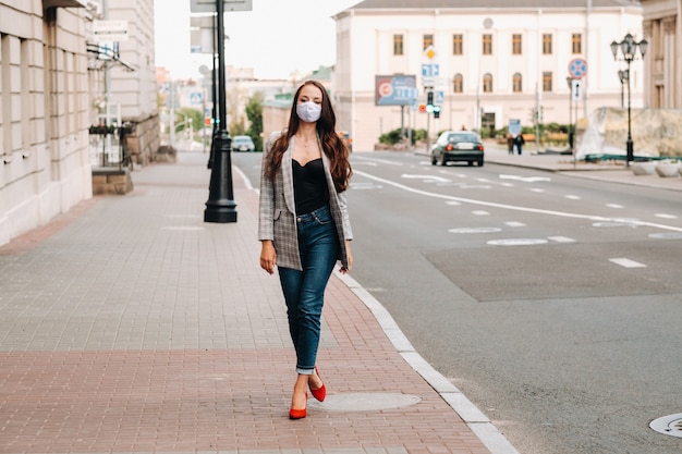 Covid-19 e conceito de PM2.5 de poluição do ar. Pandemia, retrato de uma jovem usando máscara protetora na rua. Saúde e segurança do conceito.