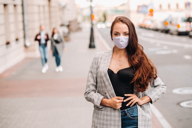 Covid-19 e conceito PM2.5 de poluição do ar. Pandemia, retrato de uma jovem usando máscara protetora na rua. Saúde e segurança do conceito.