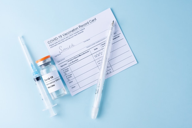 Covid-19-Impfstoffflasche, Impfpasskarte, Spritze, Stift, Kopierraum, Nahaufnahme. Coronavirus-Impfkonzept.