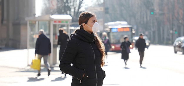 COVID-19 Junge Frau in der Stadtstraße mit Gesichtsmaske zum Schutz vor der Ausbreitung der Coronavirus-Krankheit 2019.