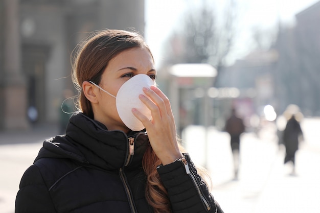 COVID-19 Junges Mädchen in der Stadtstraße, das Gesichtsmaske trägt, die zur Ausbreitung der Coronavirus-Krankheit 2019 schützt.