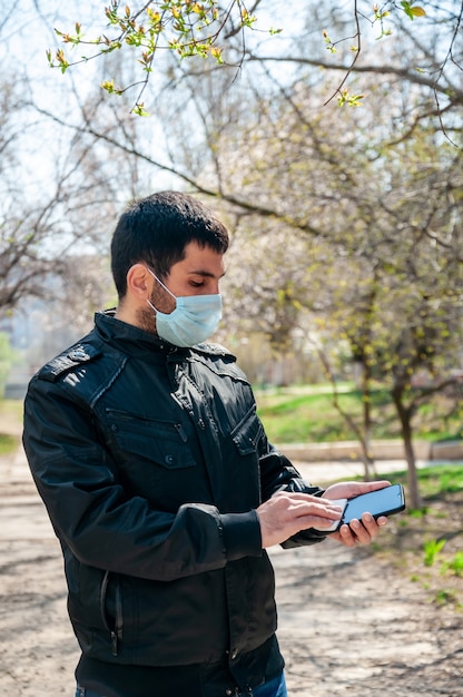 COVID-19. O homem novo ao ar livre desinfeta o guardanapo antibacteriano do telefone.