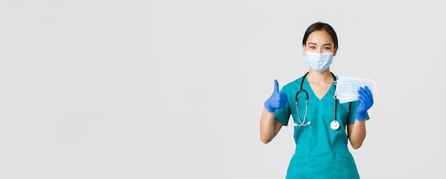 Covid-Coronavirus-Krankheit Gesundheitspersonal Konzept lächelnde asiatische Arztkrankenschwester in Scrubs und Gummi...