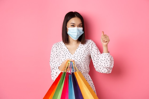 Covid pandemia y concepto de estilo de vida hermosa mujer asiática de compras en centros comerciales en máscara médica sosteniendo ...