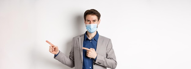 Covid pandemia e conceito de negócios gerente masculino confiante em terno e máscara médica mostrando ponto de passagem