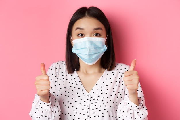 Covid pandemia e estilo de vida conceito de mulher asiática de apoio na máscara facial mostrando thumbsup aprovar um ...