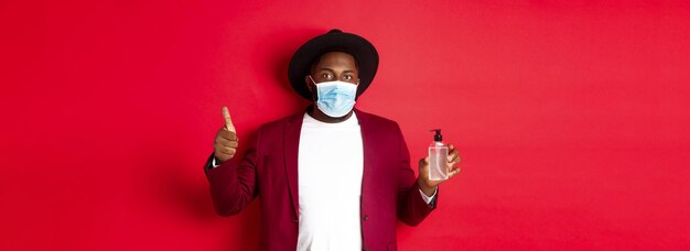 Foto covid quarantäne- und urlaubskonzept junger afroamerikanischer mann in medizinischer maske mit händedesinfektion