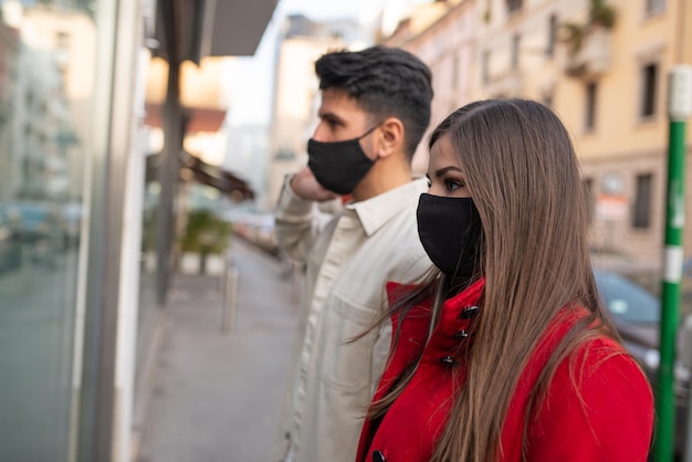 Covid- und Coronavirus-Einkaufspaar, das in einer Stadt spazieren geht