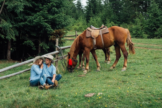 Cowboy e cowgirl nas montanhas com seu cavalo
