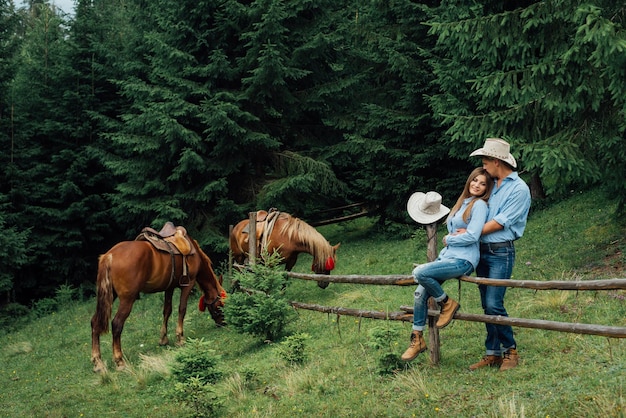 Cowboy e cowgirl nas montanhas com seus cavalos