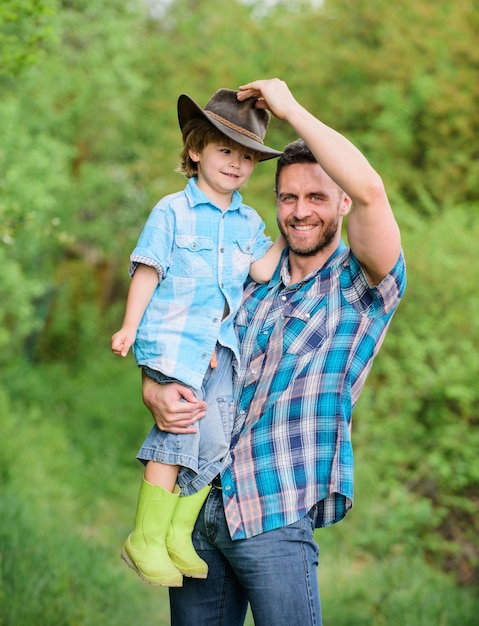 Foto cowboy fofo em crescimento fim de semana na fazenda garotinho e pai no fundo da natureza espírito de aventuras pequeno ajudante no jardim criança se divertindo pai vaqueiro família de fazenda férias na fazenda dos pais