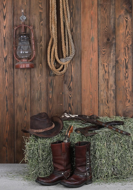 Cowboyhut, Stiefel und Waffe auf einem Holzboden