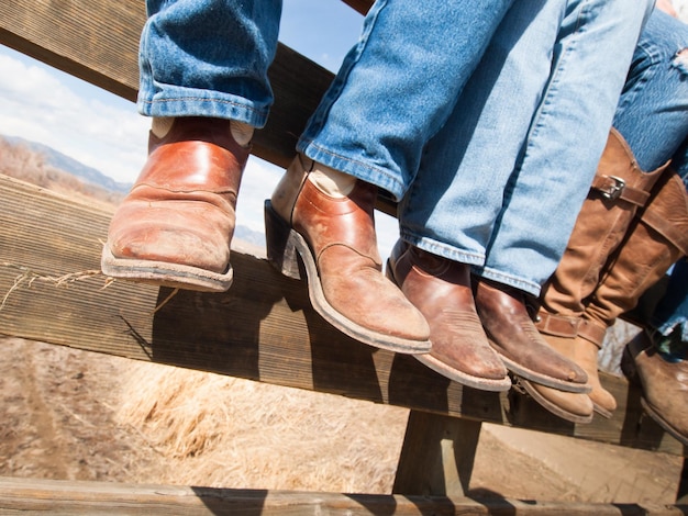 Cowboys und Cowgirls, die auf Holzzaun sitzen.