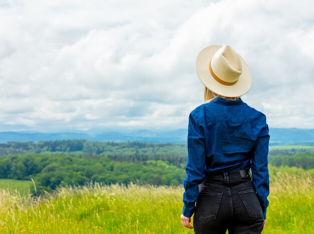 Cowgirl loira de chapéu no Prado com montanhas