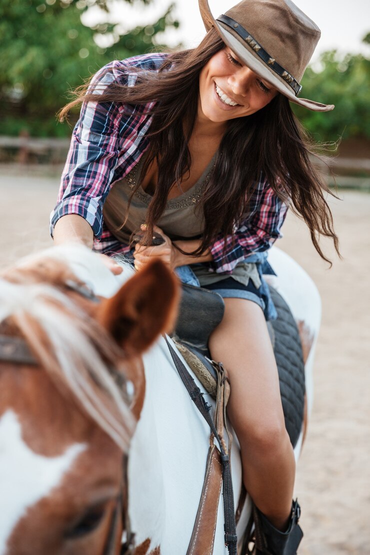 Foto cowgirl muito jovem e alegre desfrutando de um passeio a cavalo na aldeia