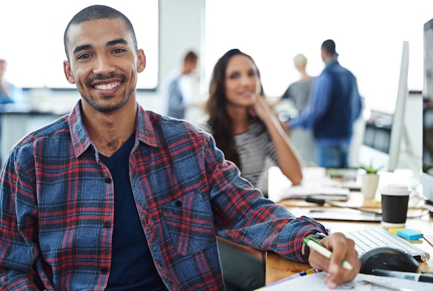 Coworking feliz e retrato de um homem no escritório com equipe para notas de projeto criativo na empresa brasileira Empregado entusiasmado e pessoa com sorriso para produtividade em colaboração ou planejamento de trabalho em equipe