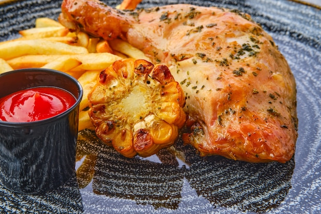 coxa de frango assada com batatas fritas perto de ketchup e milho grelhado