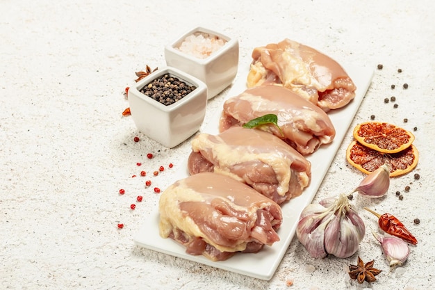 Coxa de frango crua sem ossos ou pele. Um ingrediente útil para preparar alimentos saudáveis, especiarias, alho. Fundo de massa leve, copie o espaço