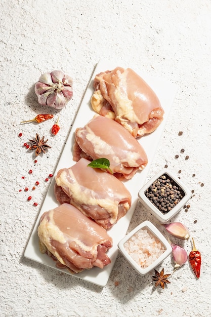 Coxa de frango crua sem ossos ou pele. Um ingrediente útil para preparar alimentos saudáveis, especiarias, alho. Luz dura de moda, sombra escura, fundo de massa leve, vista superior