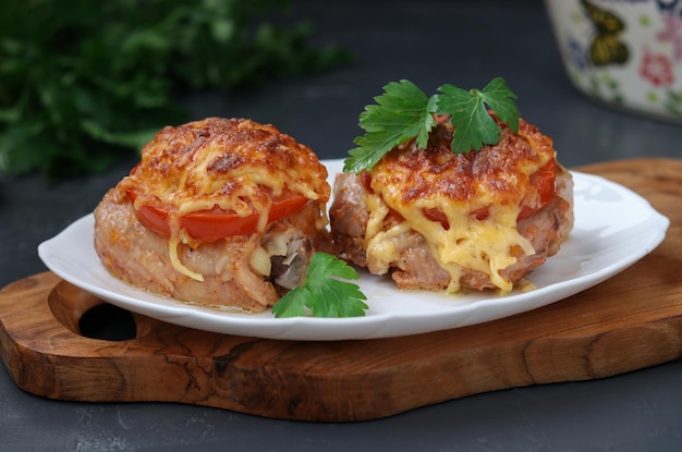 Foto coxas de frango com tomates e queijo dispostas em pratos em tábuas de madeira