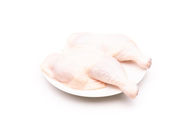 Coxas de frango cru em prato branco isolado em branco