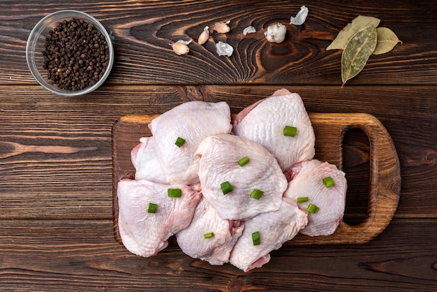 Coxas de frango cru na mesa de madeira escura.