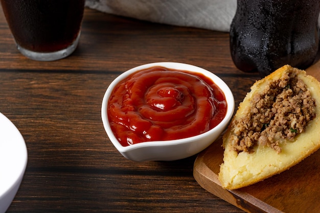 coxinha, cortada por la mitad rellena de carne. también salsa de ketchup