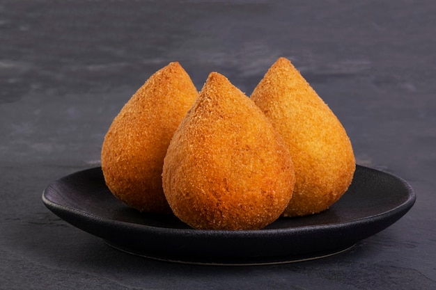 Coxinha frita tradicional en una placa negra sobre un fondo de pizarra - snack brasileño.