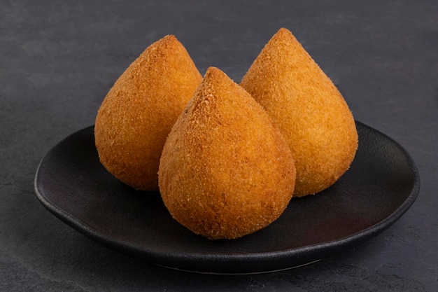 Coxinha frita tradicional en una placa negra sobre un fondo de pizarra - snack brasileño.