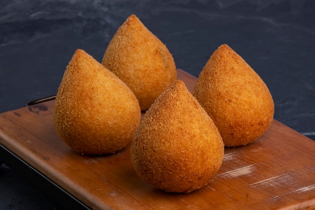 Coxinha frita tradicional sobre una tabla de madera sobre piedra pizarra.