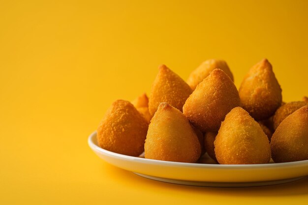 Foto coxinha, lanche tradicional brasileiro recheado de frango e frito em fundo amarelo