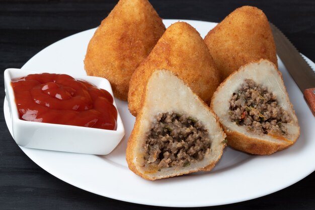 Coxinha de mitades y carne entera con kétchup.