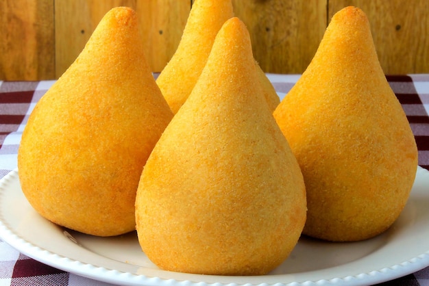 Coxinha en el plato bocadillos de cocina tradicional brasileña rellenados con pollo en una mesa de madera rústica