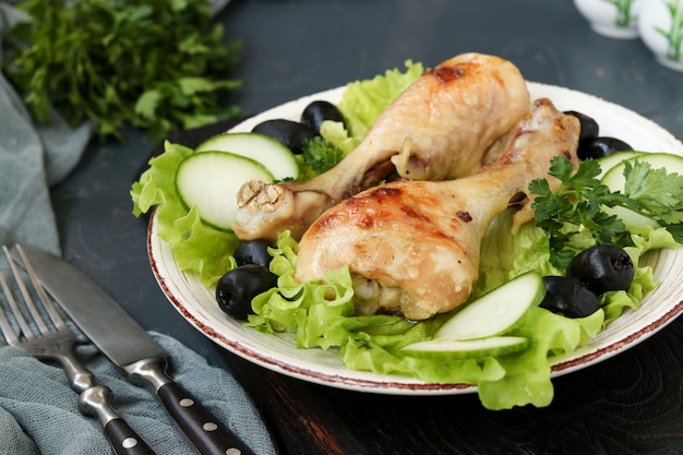 Coxinhas de frango servidas com pepinos, azeitonas pretas e alface em um prato