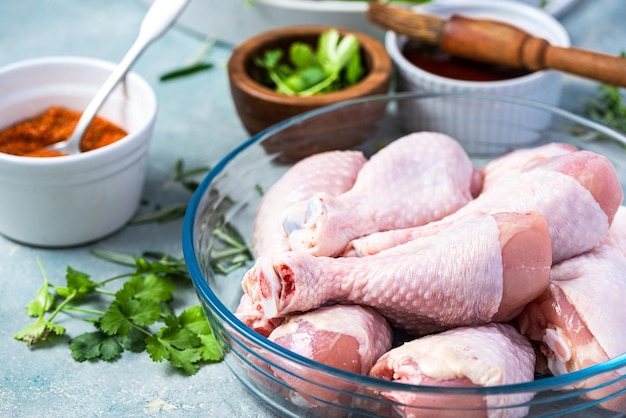 Coxinhas de pernas de frango cru com pele em tigela de comida para preparação de churrasqueira