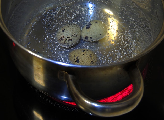 Cozimento de ovos de codorna em uma panela no fogão da cozinha