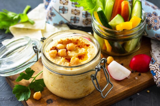 Cozinha árabe Hummus do Oriente Médio com lanches Hummus mergulho com legumes frescos em uma bancada de pedra escura