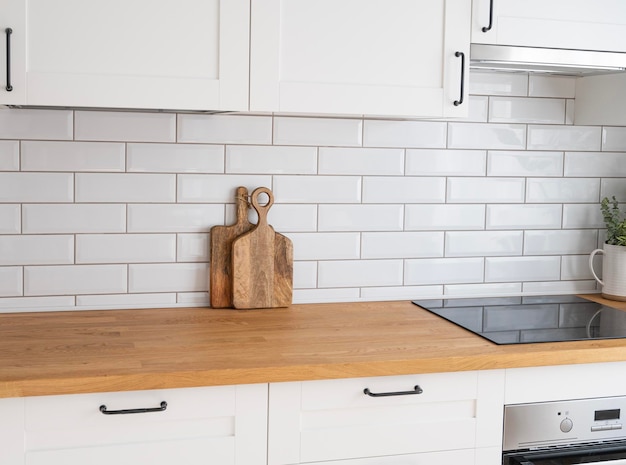 Cozinha branca aconchegante com flor de bancada de madeira e tábuas de corte em um interior minimalista com luz solar durante o dia