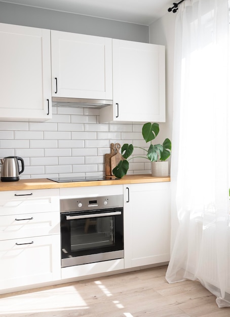 Cozinha branca aconchegante com flor de chaleira de bancada de madeira e tábuas de corte em um interior minimalista com luz solar durante o dia