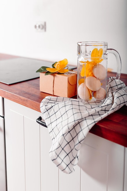 Foto cozinha branca com jarro de vidro cheio de ovos cartão de feliz páscoa com caixa de presente e ovos