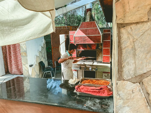 Cozinha com um chef sob o céu aberto o cozinheiro assa pizza para turistas tira comida do forno