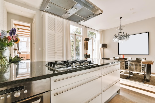 Cozinha confortável com unidade de cozinha branca e bancada de mármore preto e exaustor moderno