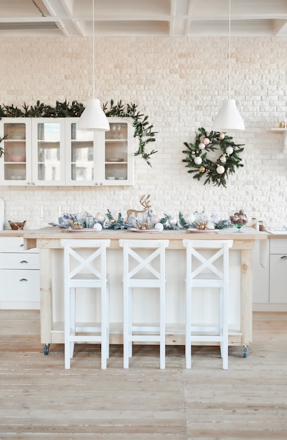 Cozinha de luz interior com decoração de natal e árvore. cozinha branca em estilo clássico. natal na cozinha. cozinha brilhante em tons de branco com o natal.