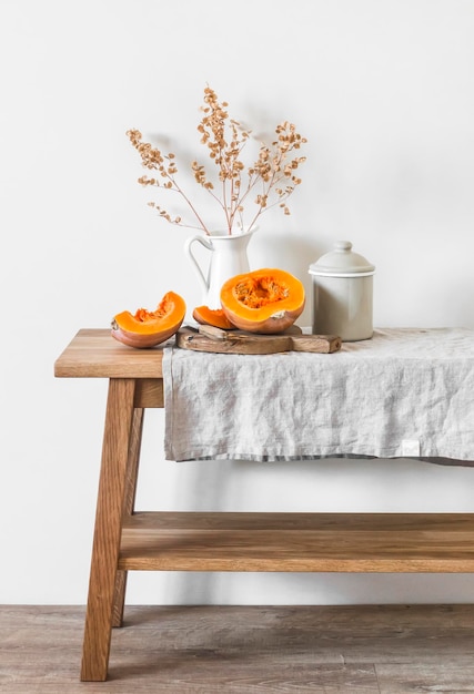 Cozinha de outono ainda corta utensílios de mesa de esmalte rústico de abóbora em uma mesa de madeira com uma toalha de linho