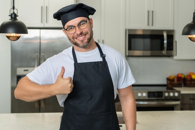 Cozinha e conceito culinário chef cozinheiro de uniforme na cozinha chef feliz cozinheiro com o polegar para cima retrato