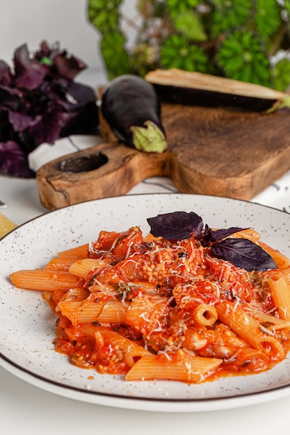 Cozinha italiana. macarrão penne com molho de tomate berinjela, manjericão roxo e queijo parmesão.