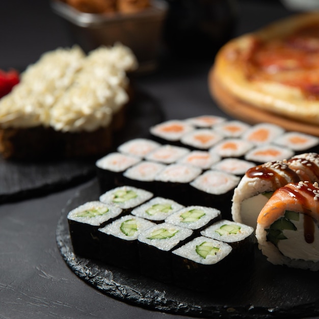 cozinha japonesa vários tipos de rolos de sushi com pizza em um banner de sushi de fundo preto
