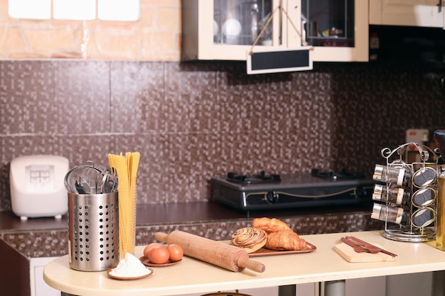 Cozinha limpa com vários ingredientes e utensílios de cozinha com pão na mesa.